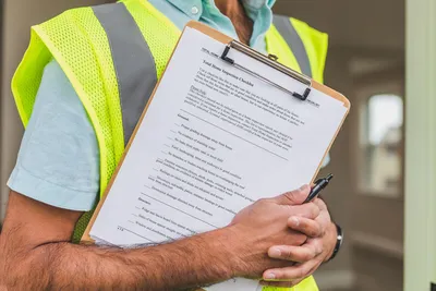Close-up of home inspector holding a checklist on a clipboard with a pen.